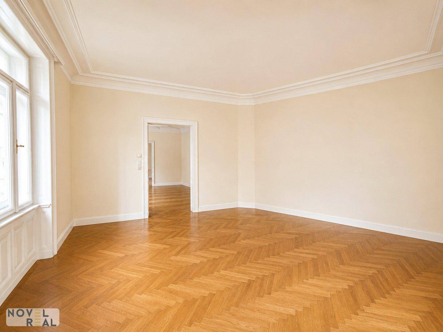Helles Zimmer mit Fischgrätparkett und hohen Decken, ideal für Wohnzwecke.