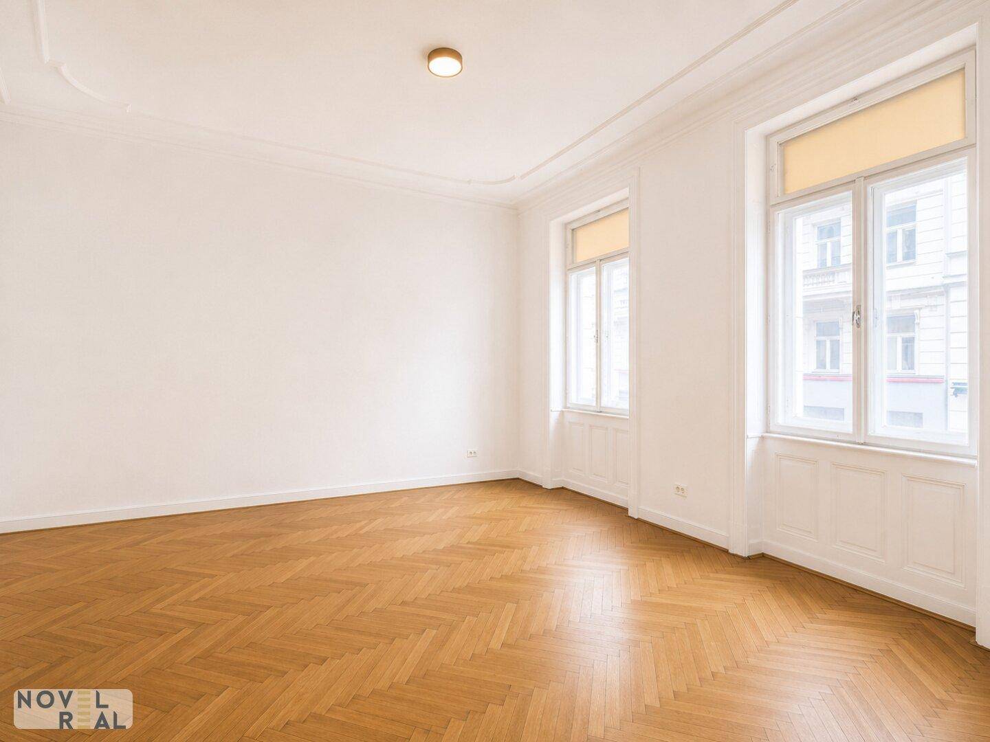 Helles Zimmer mit Fischgrätparkett und hohen Decken, bereit zur individuellen Gestaltung.