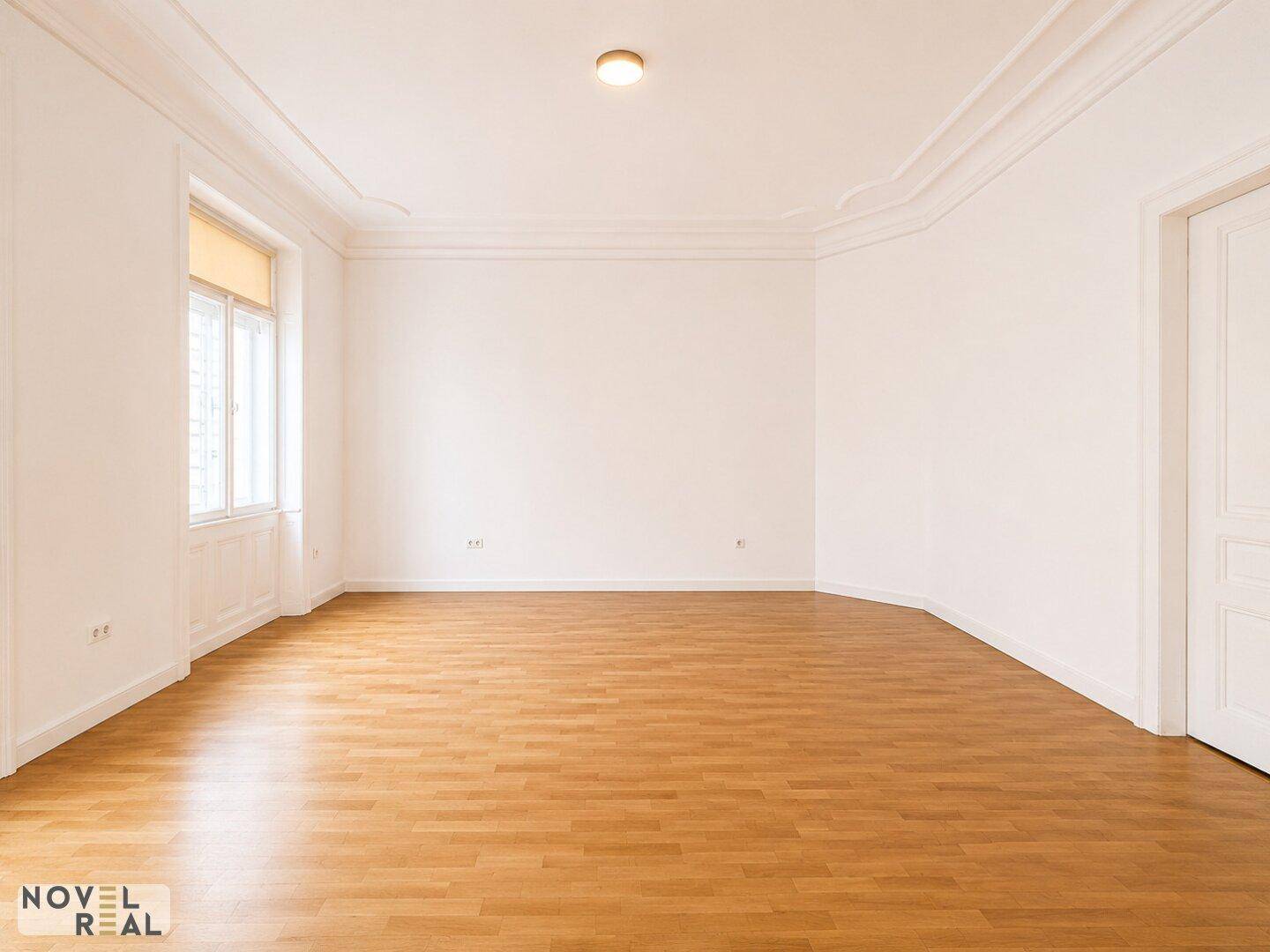 Geräumiges Zimmer mit Laminatboden und hohen Decken, bereit zur individuellen Einrichtung.