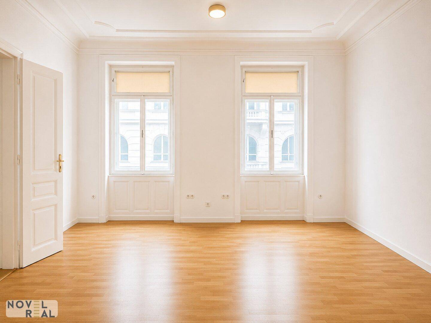 Geräumiges Zimmer mit Laminatboden und großen Fenstern, bietet viel Tageslicht.