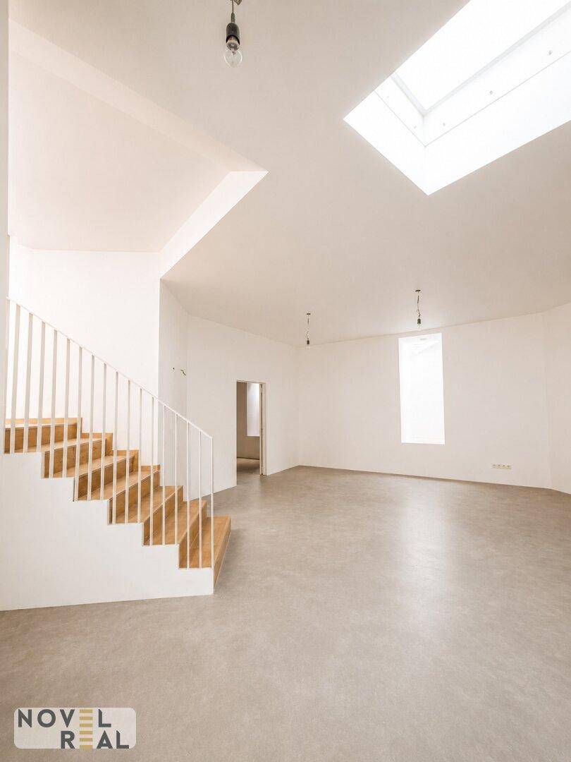 Heller Raum mit Holztreppe, Betonboden und Dachfenster, bietet viel Gestaltungspotenzial.