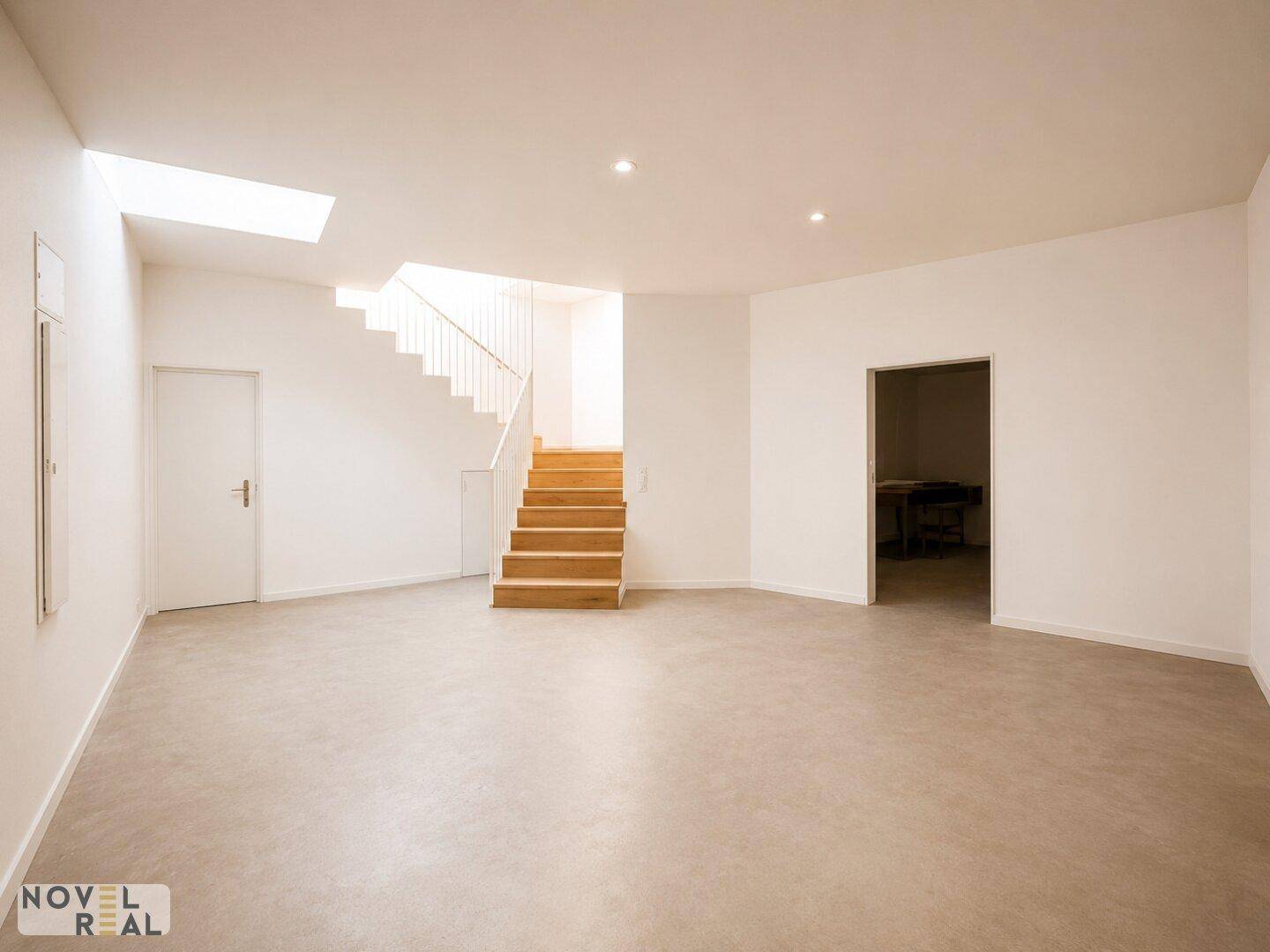 Großer, heller Raum mit Holztreppe, Betonboden und Dachfenster, ideal für offene Konzepte.