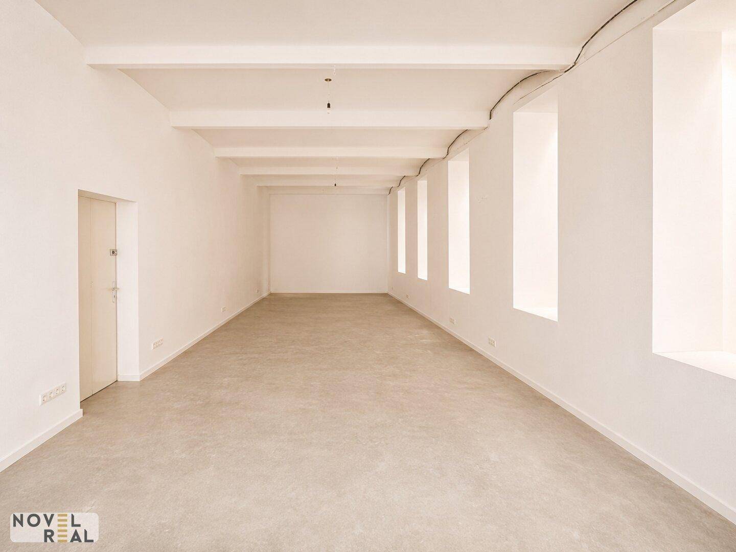 Langer, leerer Raum mit Betonboden und hohen Decken, bereit für Ausbau.