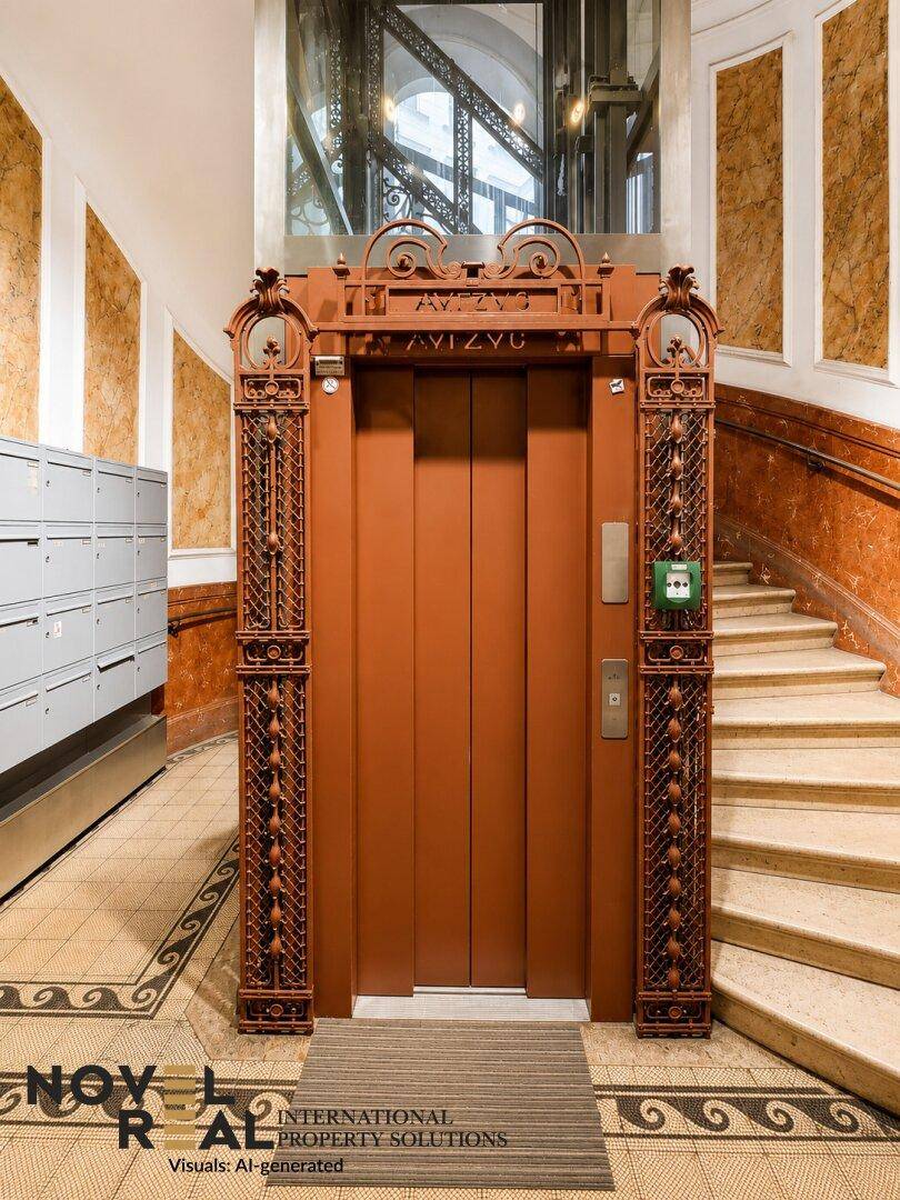 Historischer Aufzug mit kunstvoller Metallverzierung in einem eleganten Treppenhaus mit Marmor.