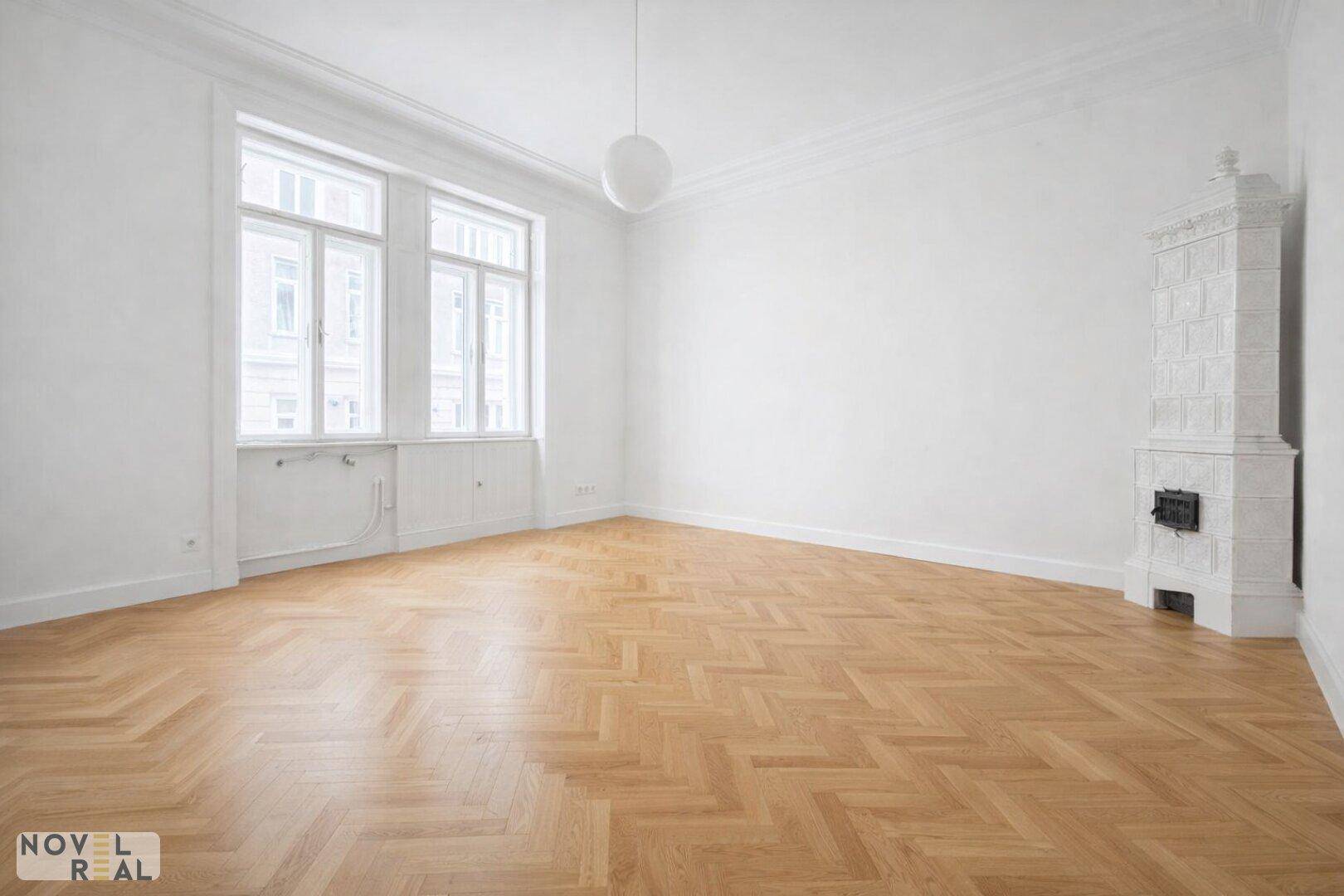 Großes, helles Zimmer mit Fischgrätparkett und einem traditionellen Kachelofen.