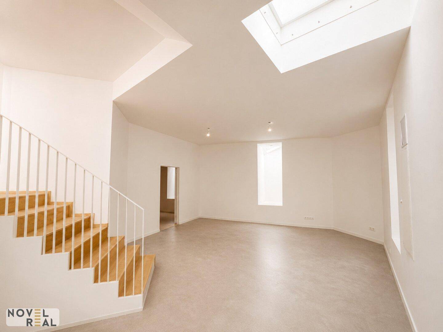 Heller Raum mit Holztreppe, Betonboden und Dachfenster, bietet viel Gestaltungspotenzial.