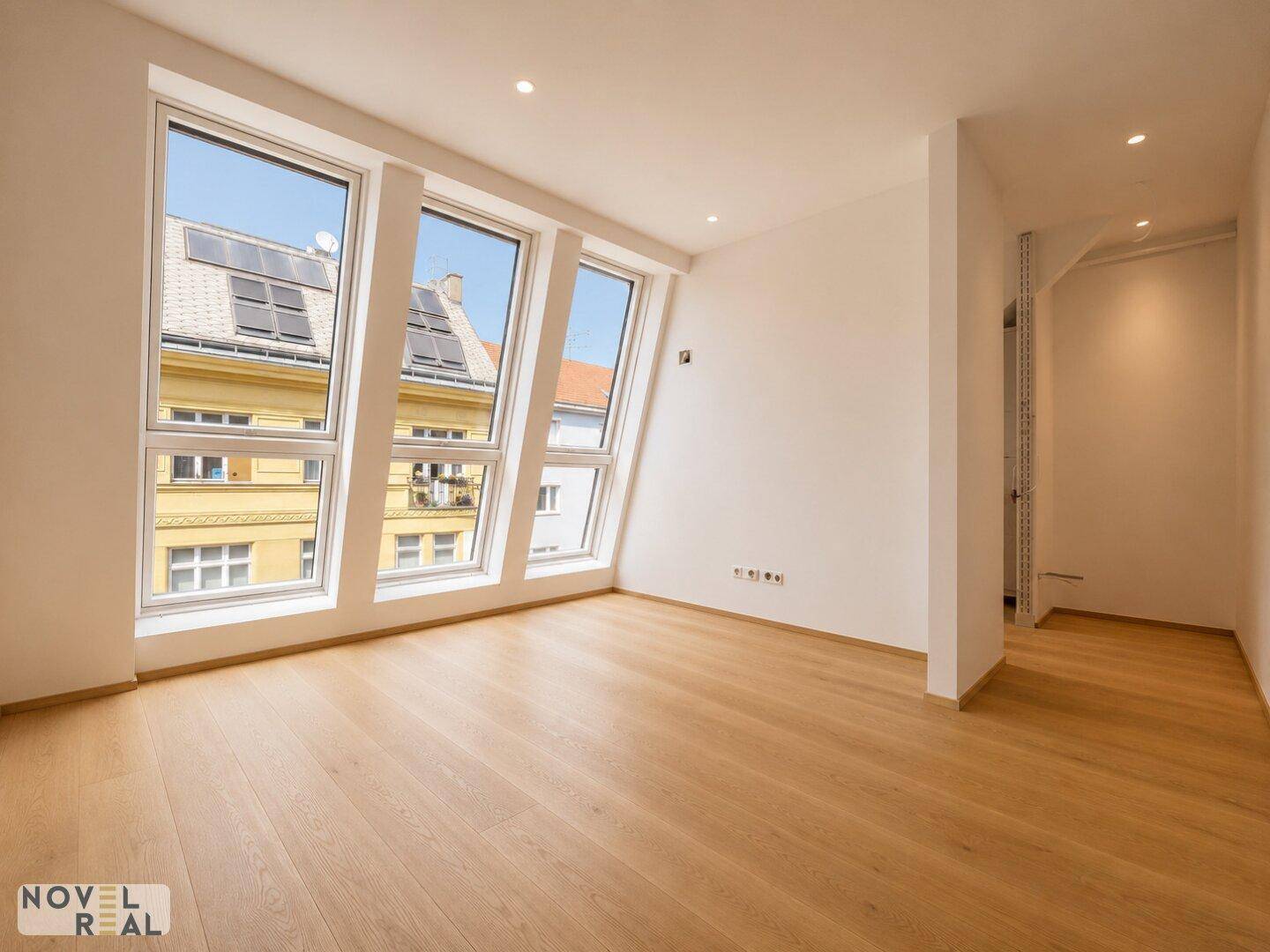 Geräumiges Schlafzimmer mit Holzfußboden, hohen Fenstern und Blick auf die Stadt.
