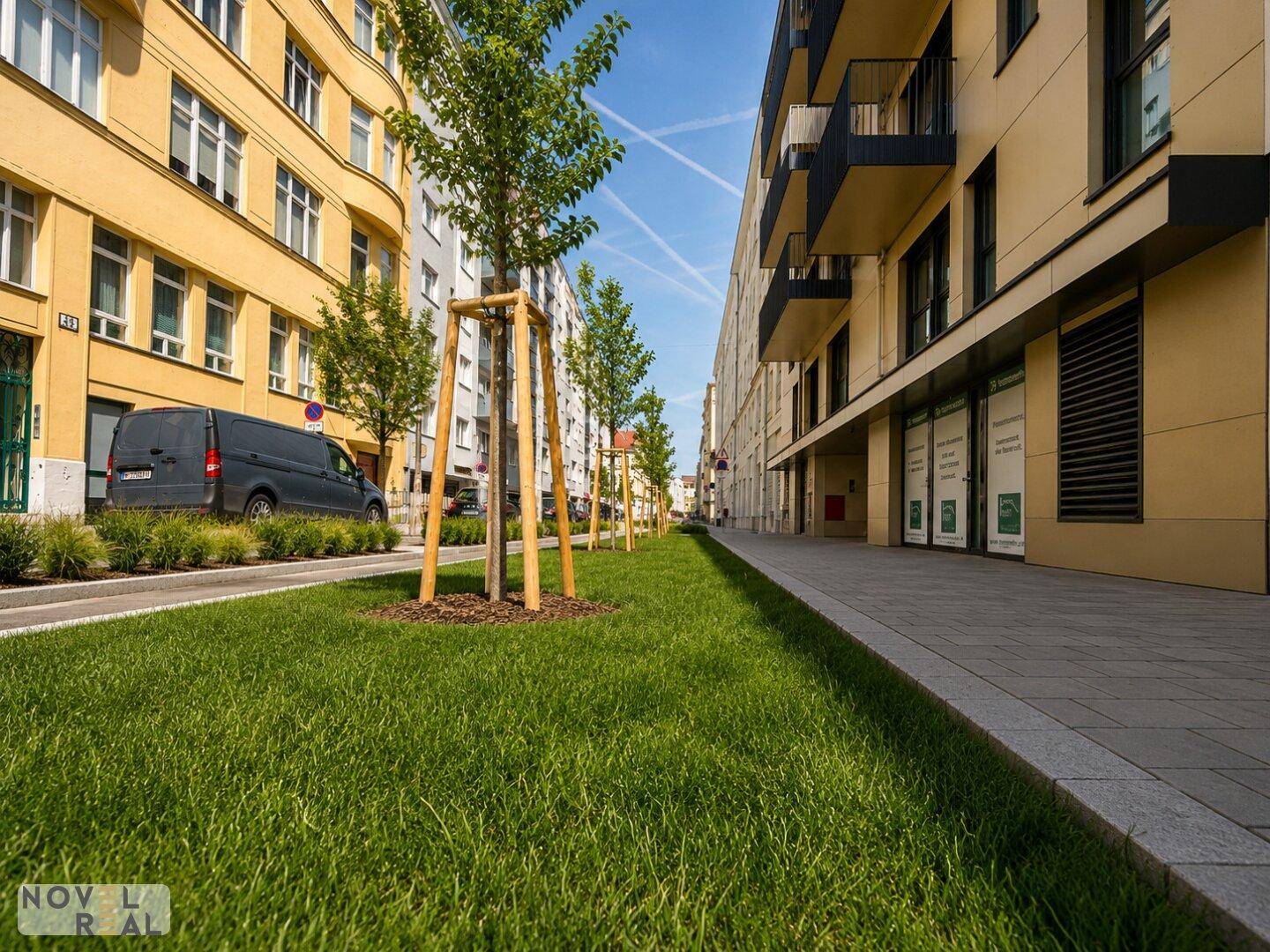 Moderne Stadtstraße mit jungen Bäumen, Grünstreifen und neuen Wohngebäuden.