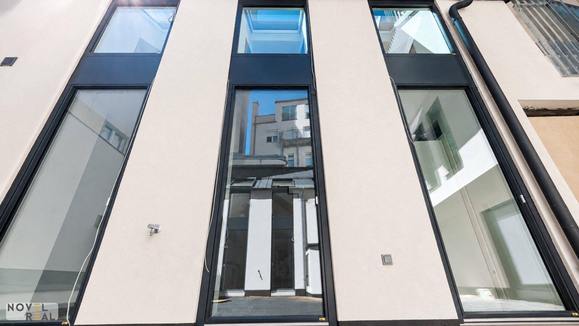 Vertikale Ansicht einer modernen Gebäudefassade mit hohen, schmalen Fenstern und klaren Linien.