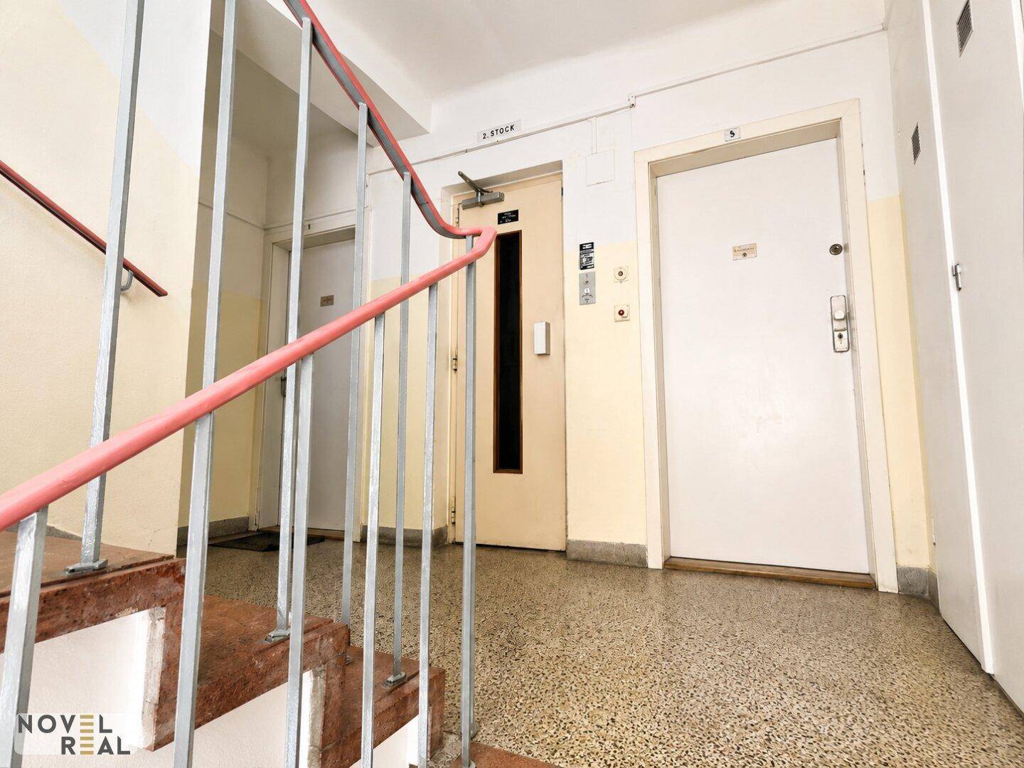 Treppenhaus mit Aufzug und Zugang zu den einzelnen Wohneinheiten, gut beleuchtet.