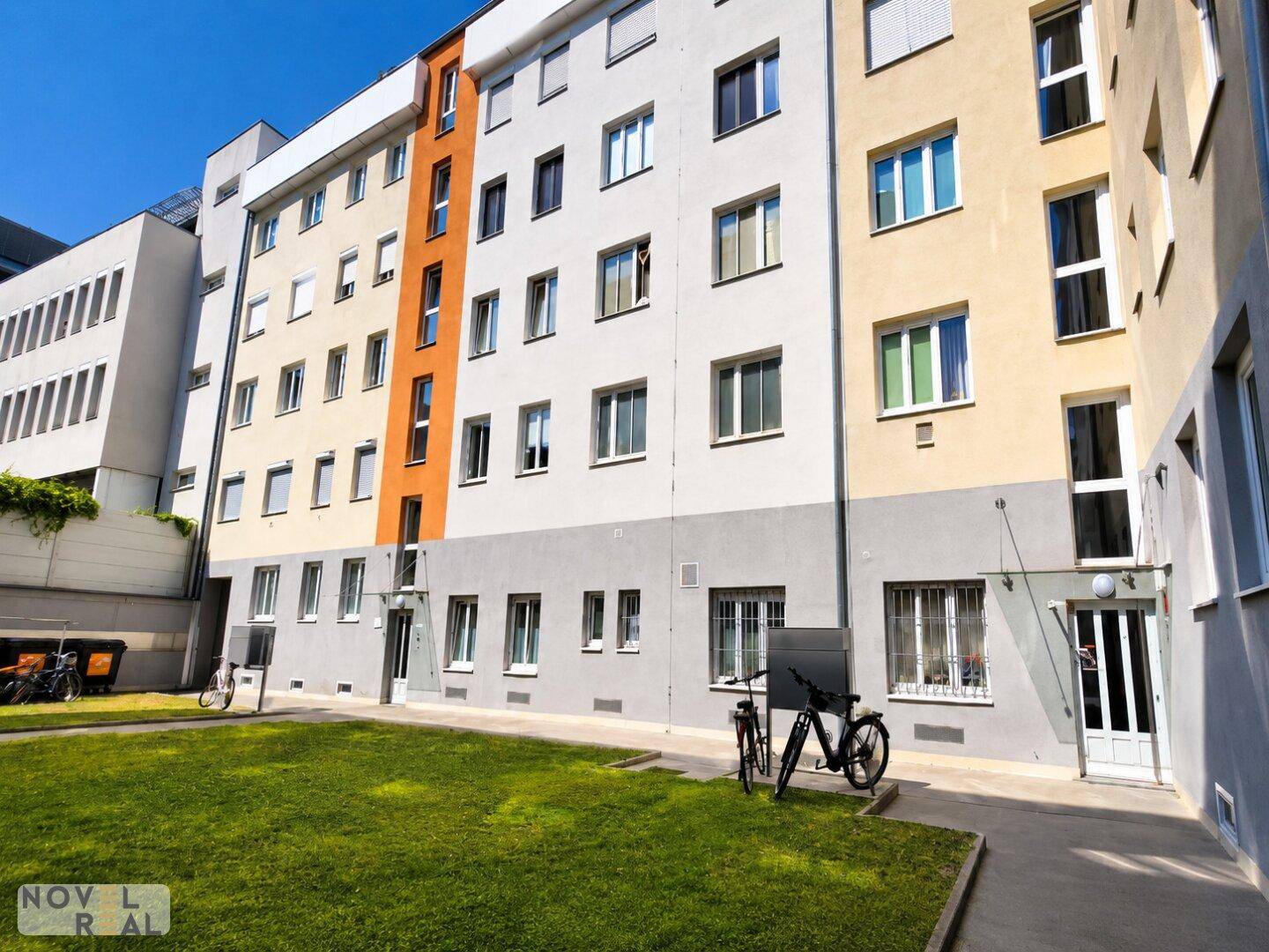 Mehrstöckiges Wohngebäude mit moderner Fassade und gepflegter Grünfläche im Vordergrund.