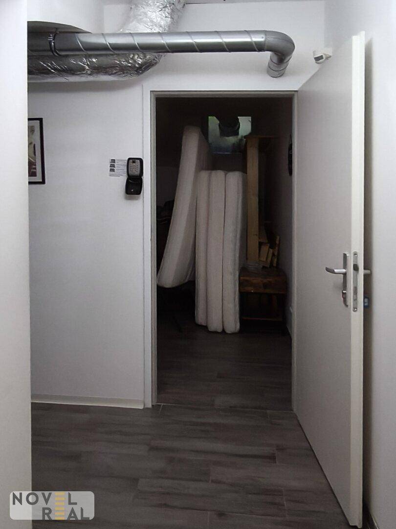 Eingang zu einem Abstellraum mit gelagerten Matratzen und sichtbaren Rohrleitungen an der Decke.