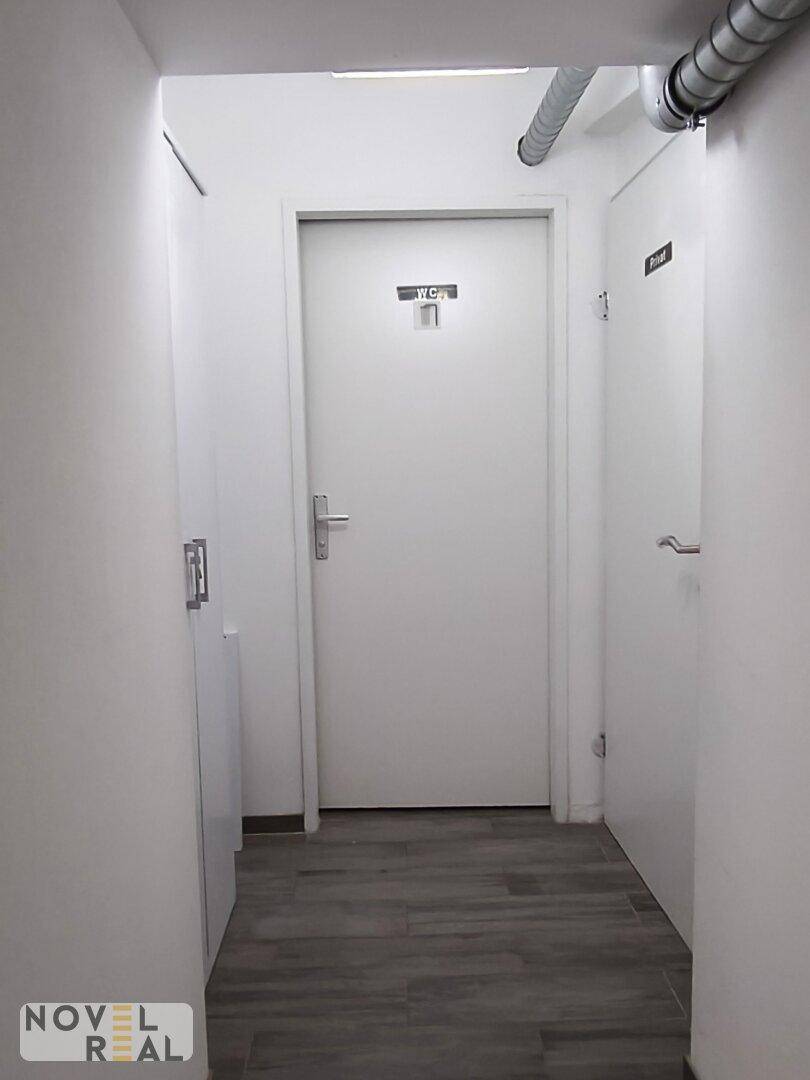 Flur mit mehreren weißen Türen, darunter eine mit der Aufschrift "WC 1", und Fliesenboden in Holzoptik.