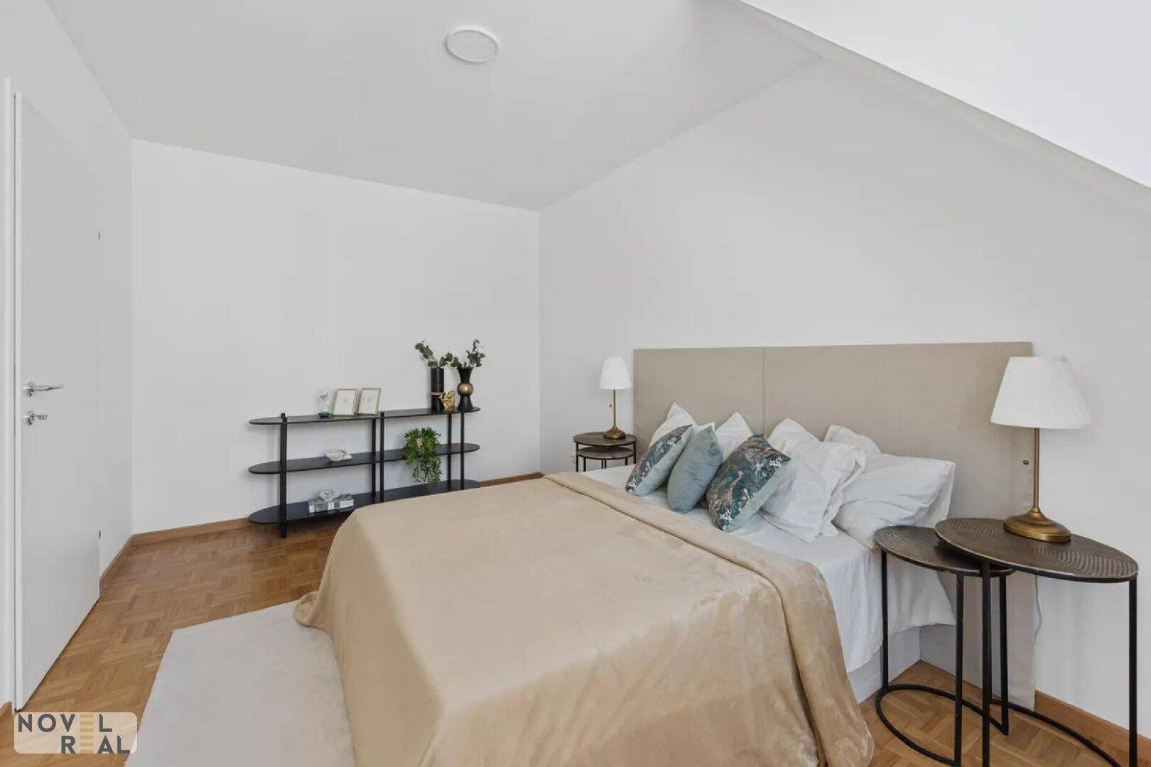 Gemütliches Schlafzimmer mit Parkettboden, Dachschräge und schlichter Einrichtung.