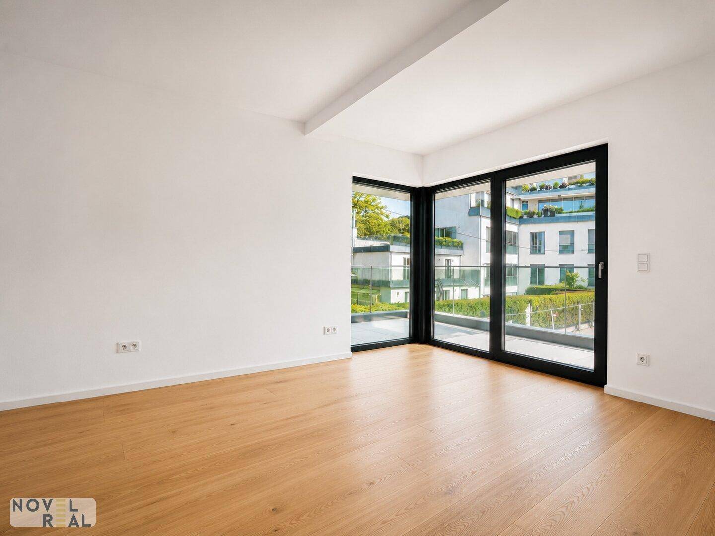 Heller Raum mit Parkettboden und Eckfenstern, die einen Blick auf die moderne Architektur bieten.