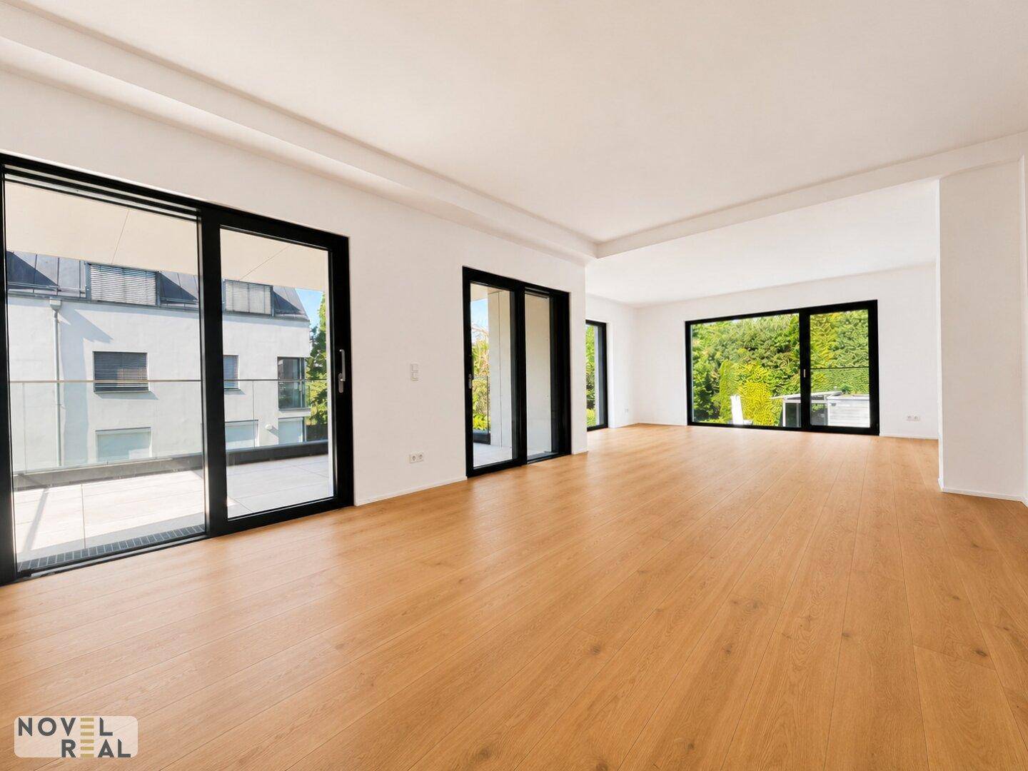 Weitläufiger Wohnbereich mit hellem Parkettboden und großen Schiebetüren zum Balkon.