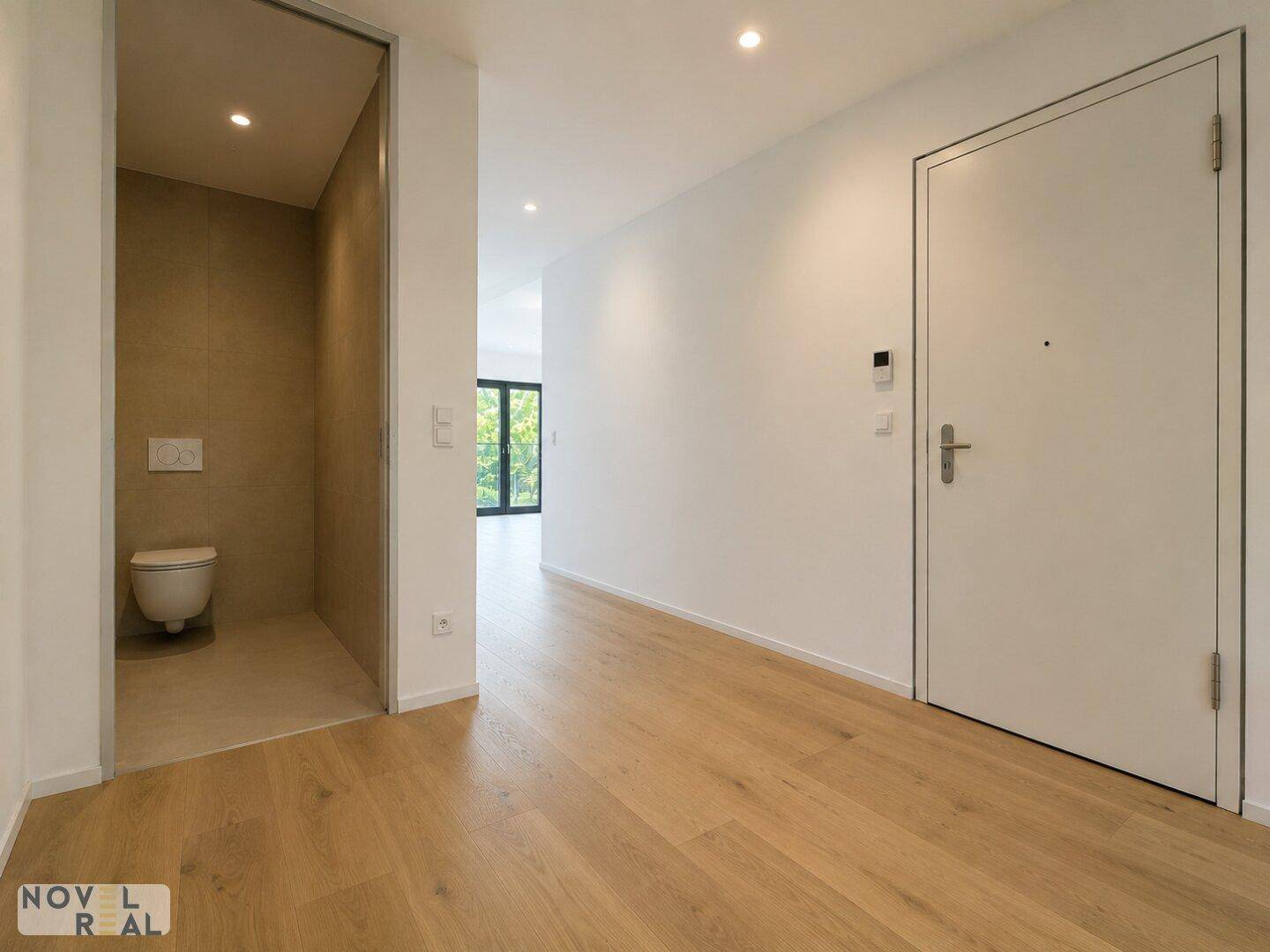 Heller Flur mit Parkettboden und Zugang zu einem modernen Gäste-WC.