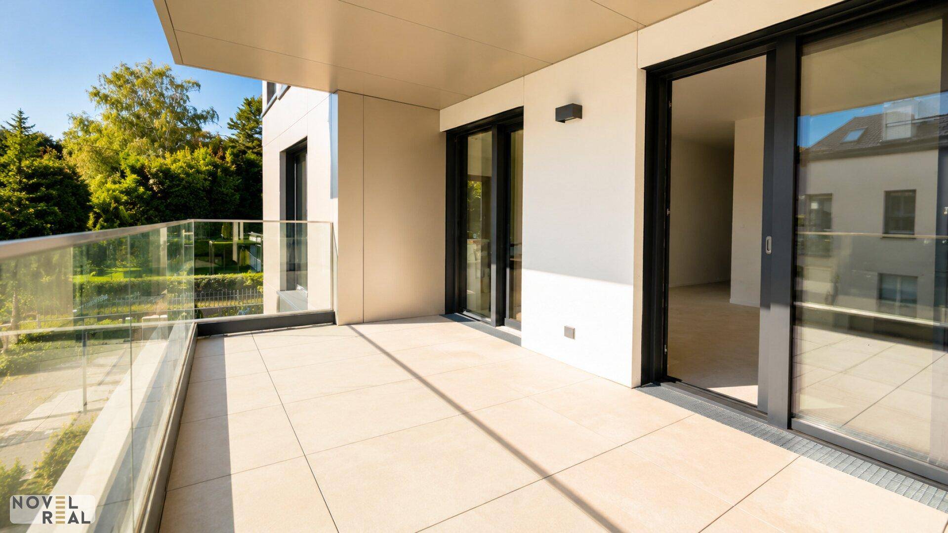 Geräumiger Balkon mit Fliesenboden und Glasgeländer, ideal für entspannte Stunden im Freien.