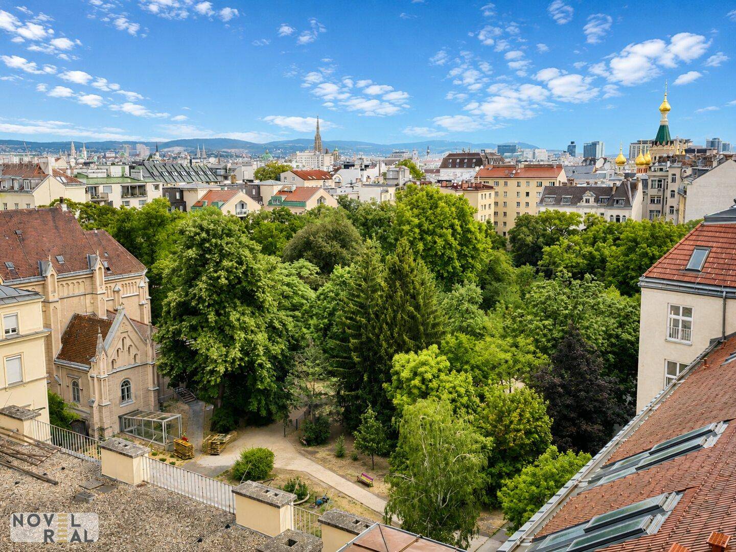 Panoramablick über die Stadt mit viel Grün und historischer Architektur unter blauem Himmel.