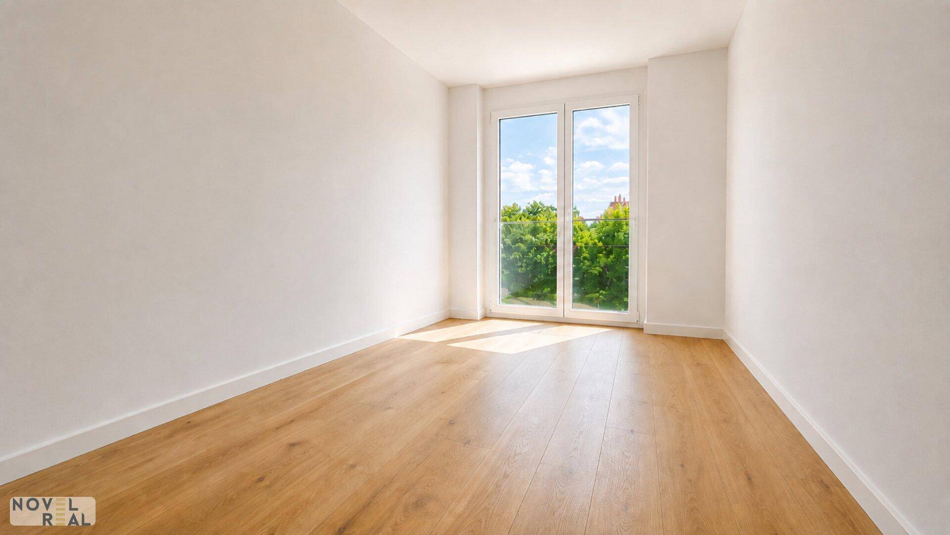 Leeres Schlafzimmer mit Holzboden und großem Fenster, das viel Tageslicht hereinlässt.