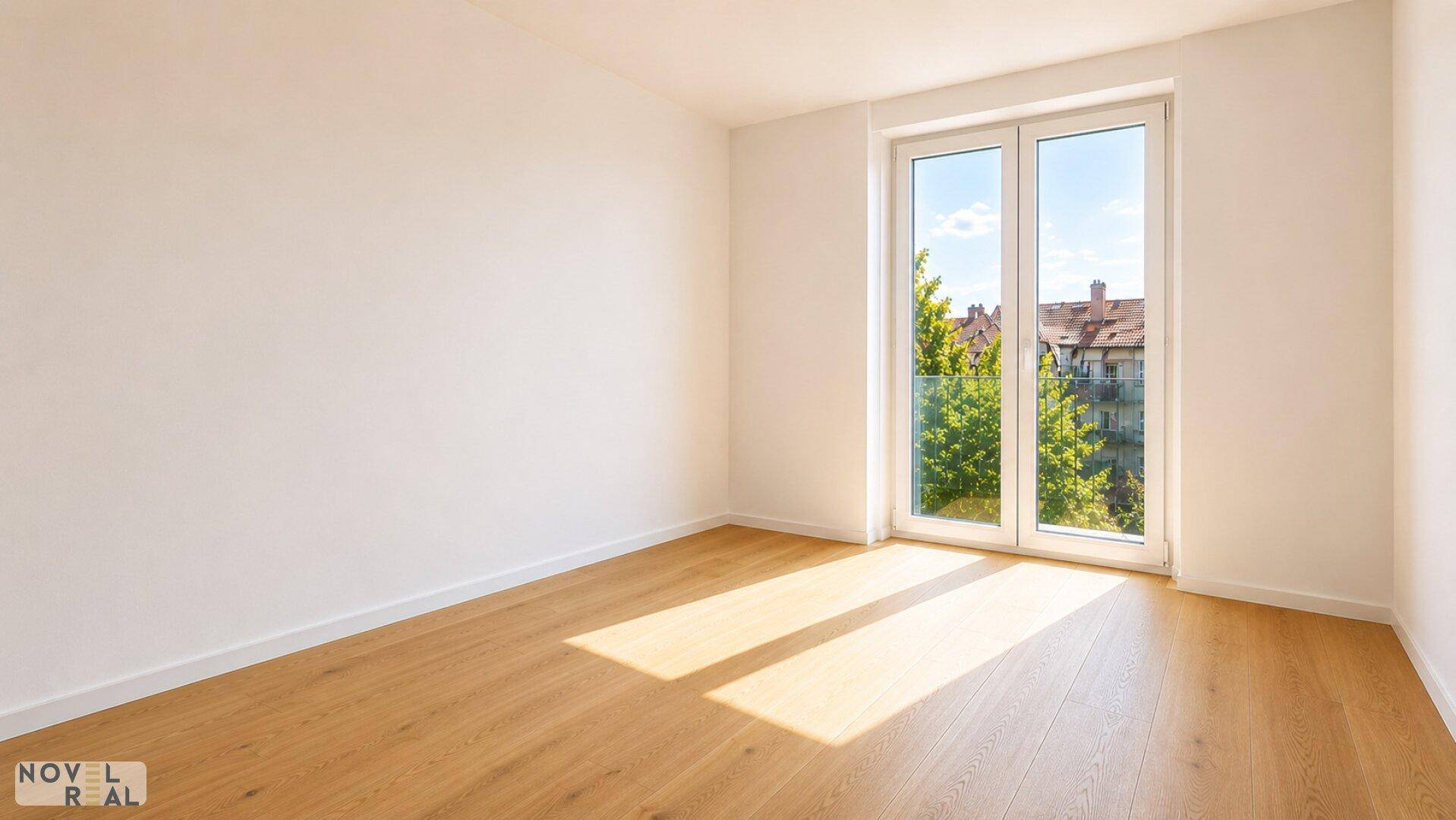 Leeres Schlafzimmer mit Holzboden und großem Fenster, das viel Sonnenlicht hereinlässt.