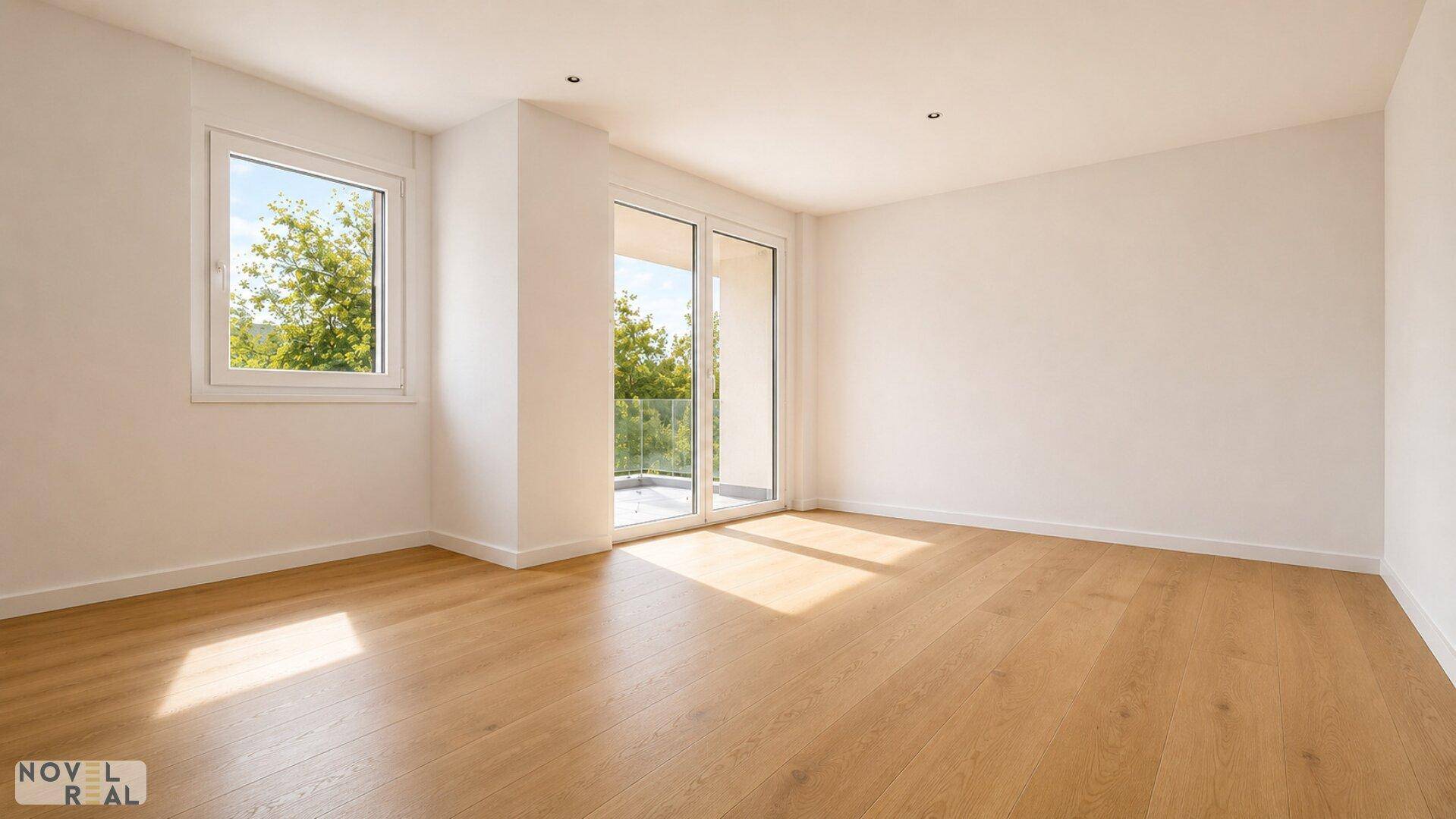 Helles, leeres Zimmer mit Holzboden, großen Fenstern und Zugang zu einem Balkon.