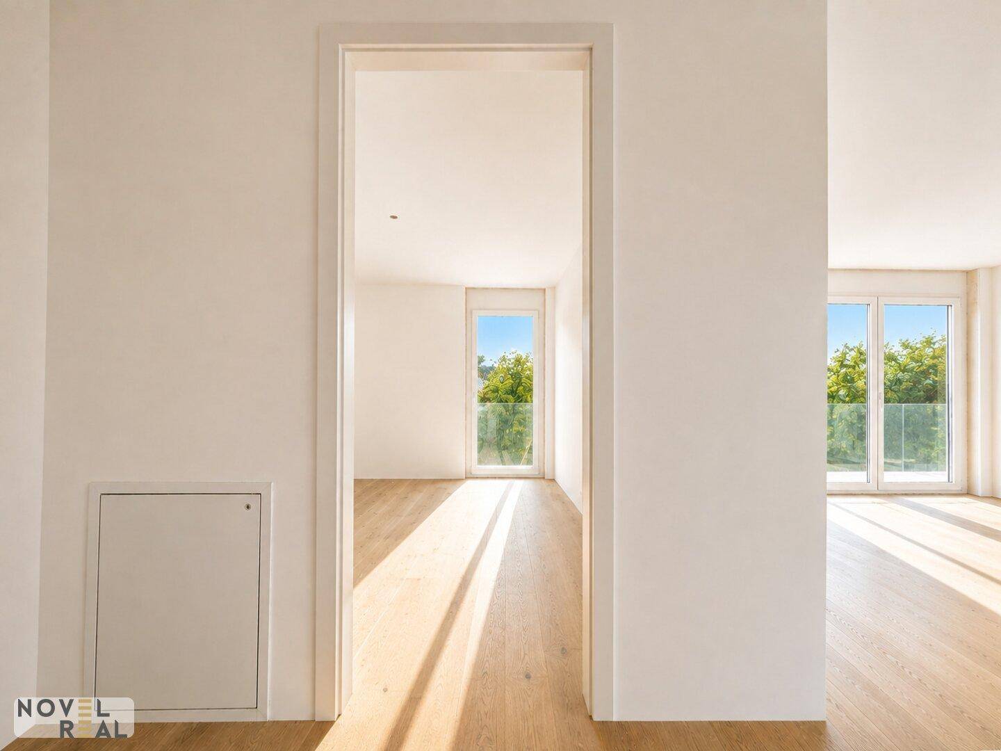 Heller Flur mit Holzboden und Blick durch eine Tür in ein weiteres lichtdurchflutetes Zimmer.