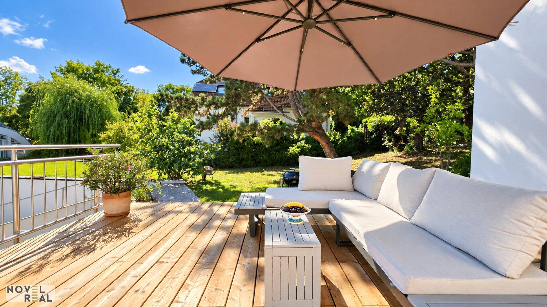 Sonnige Holzterrasse mit gemütlicher Lounge-Ecke und großem Sonnenschirm im Grünen.