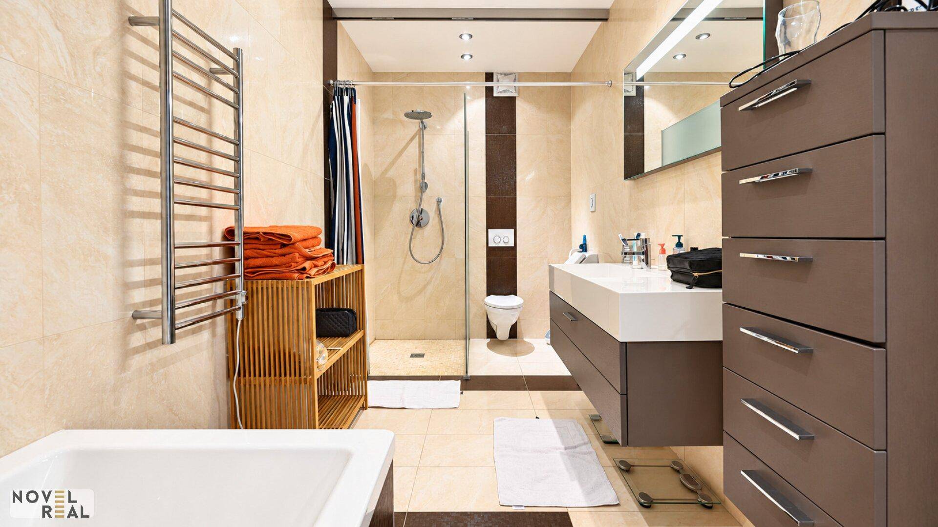 Modernes Badezimmer mit begehbarer Dusche, Badewanne, Einzelwaschbecken und beheiztem Handtuchhalter.