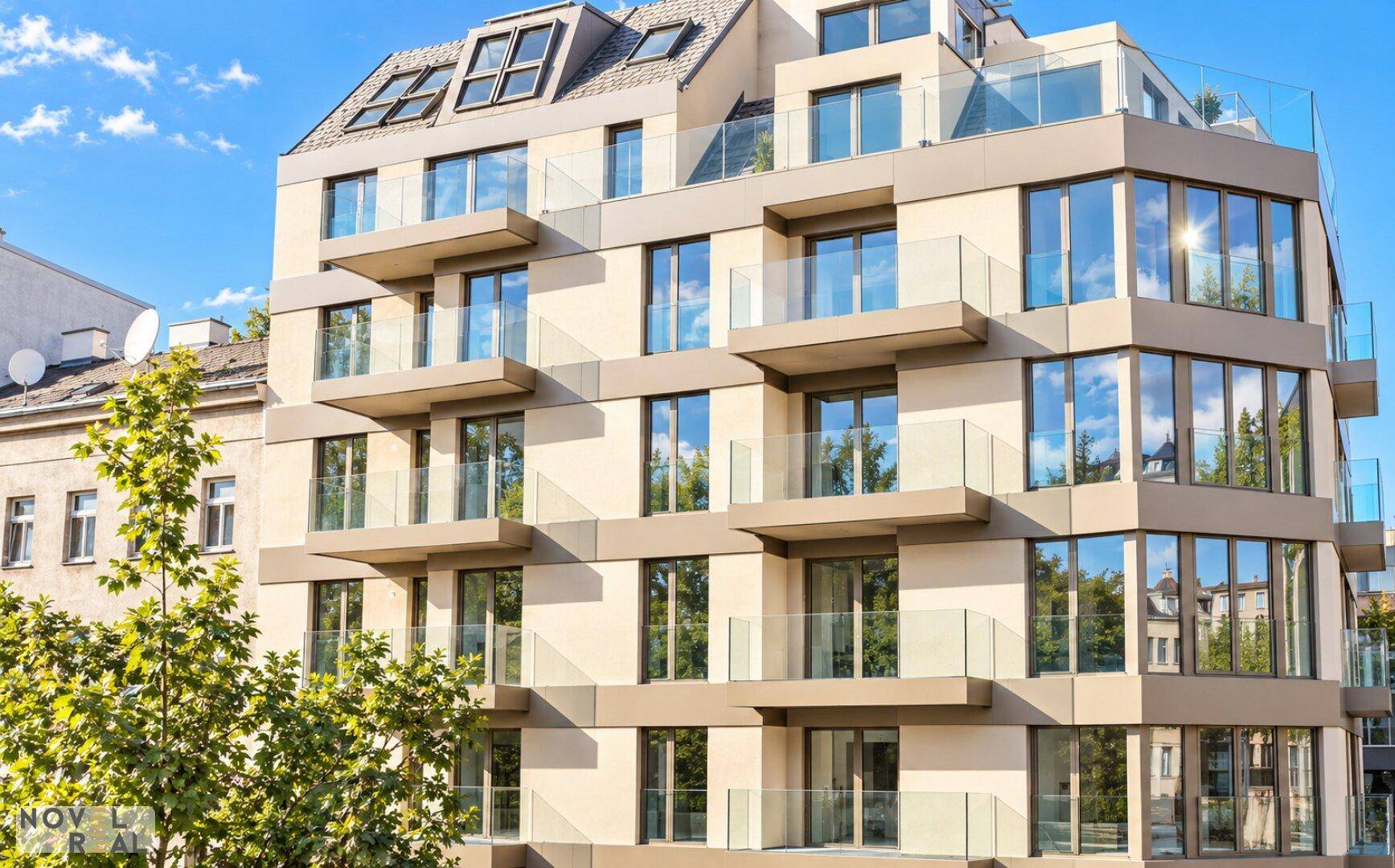 Moderne Gebäudefassade mit vielen Balkonen und großen Glasflächen unter blauem Himmel.