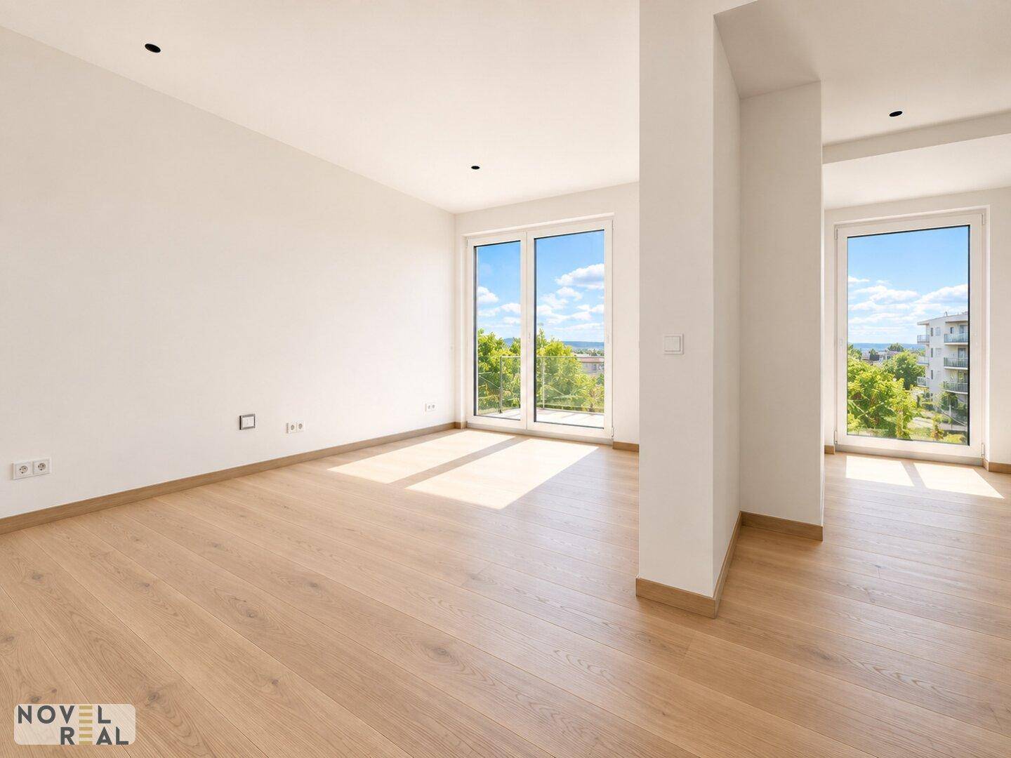 Geräumiger, heller Wohnbereich mit Holzboden und großen Fenstern, die einen weiten Blick ermöglichen.