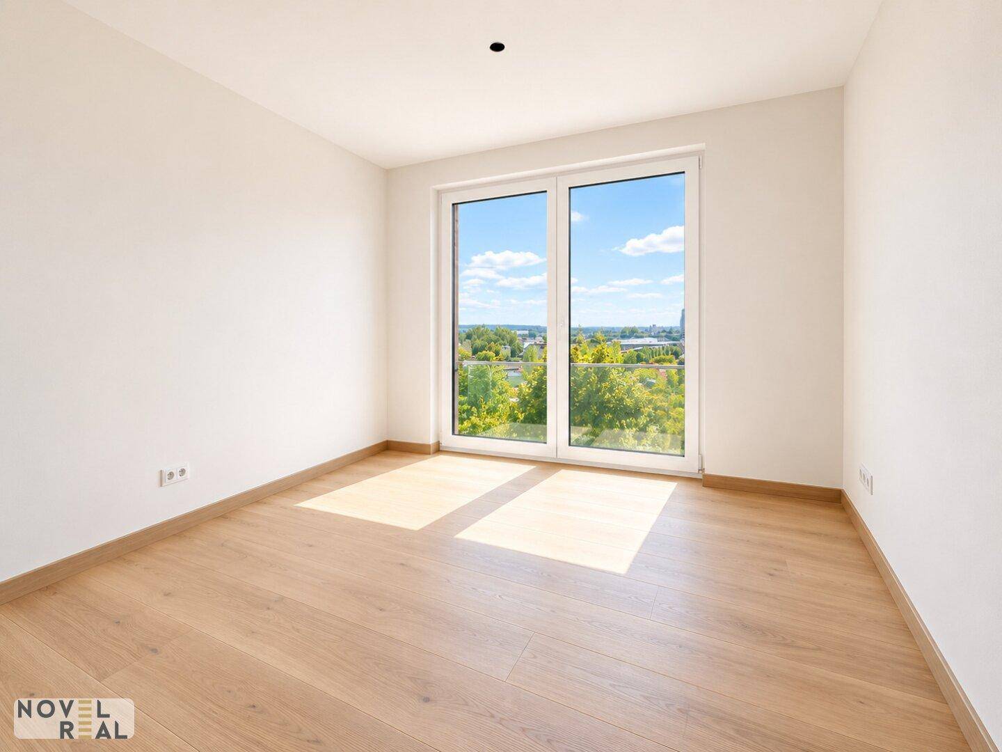 Helles Zimmer mit Holzboden und großen Fenstern, die einen schönen Ausblick bieten.