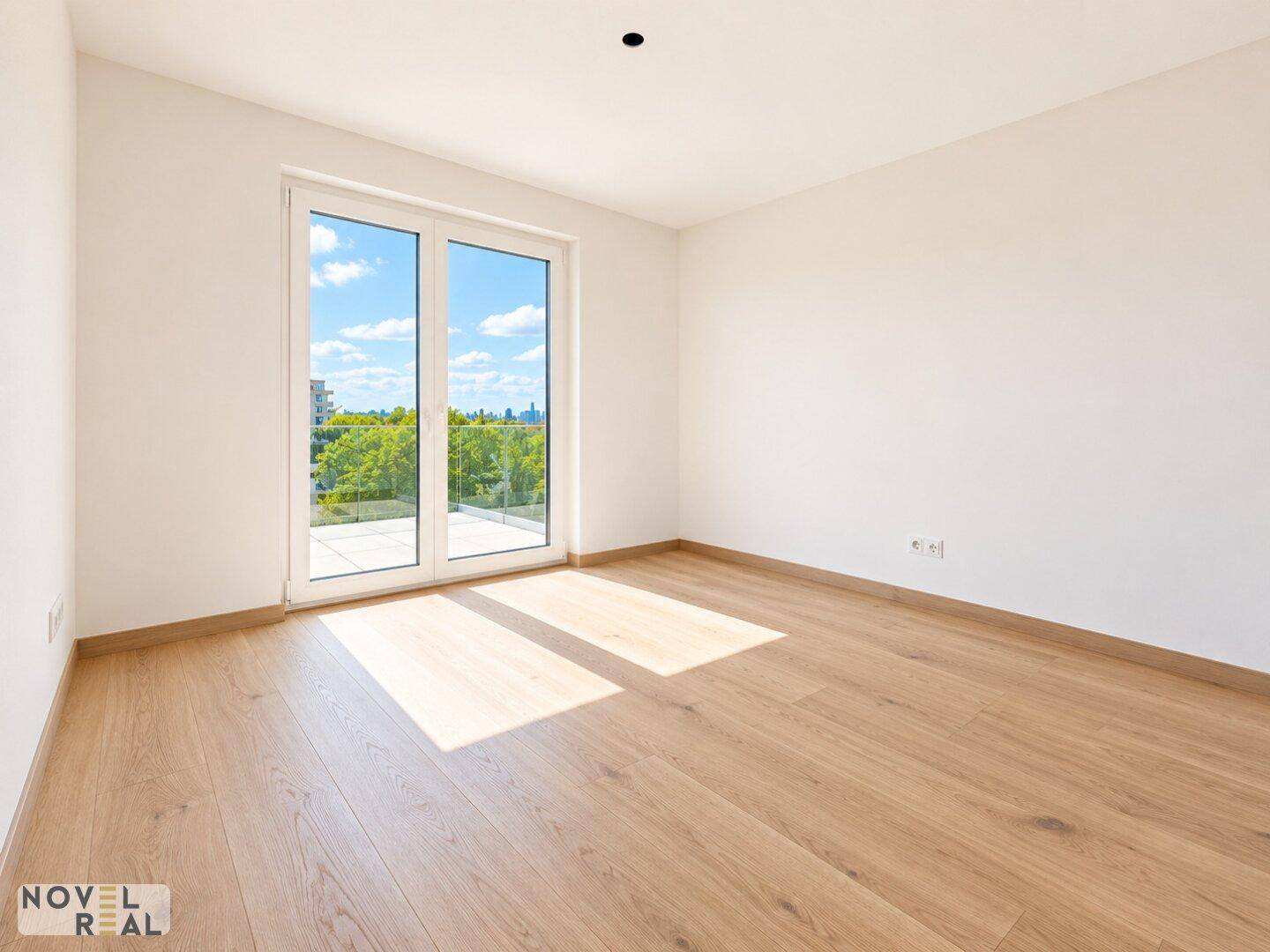 Helles Zimmer mit Holzboden und großen Fenstern, die Zugang zu einem Außenbereich bieten.