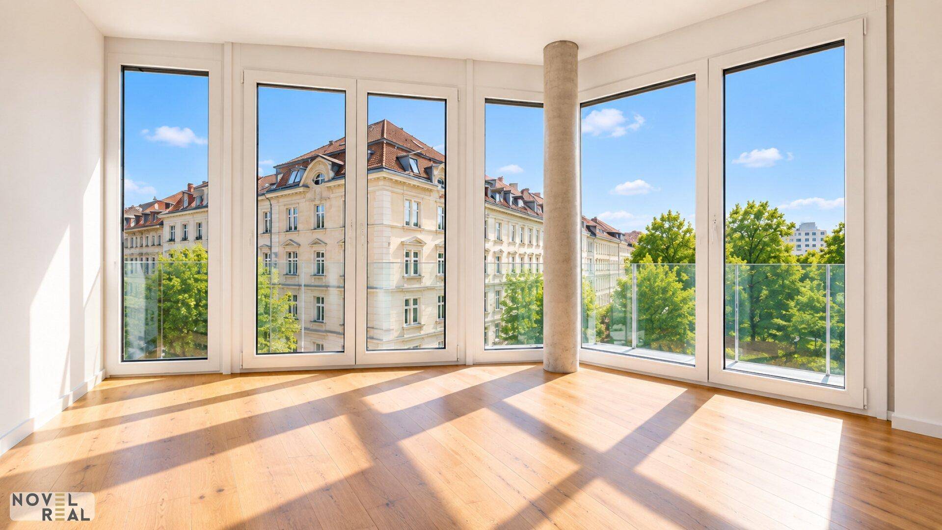 Lichtdurchfluteter Raum mit Holzboden und raumhohen Fenstern, die einen Blick auf die Stadt und Bäume bieten.