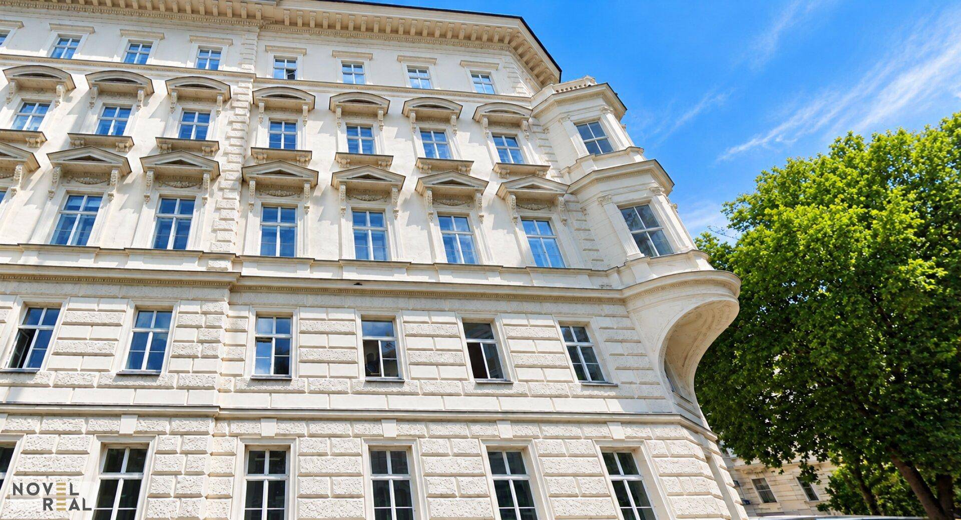 Detailansicht einer eleganten historischen Fassade mit vielen Fenstern und dekorativen Elementen unter blauem Himmel.