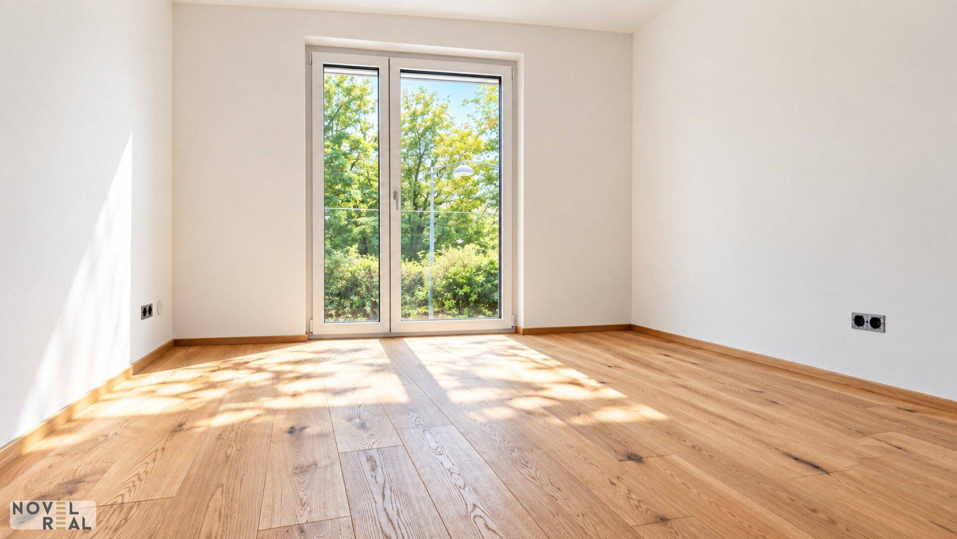 Lichtdurchfluteter Raum mit Holzboden und Zugang zu einem französischen Balkon mit Grünblick.