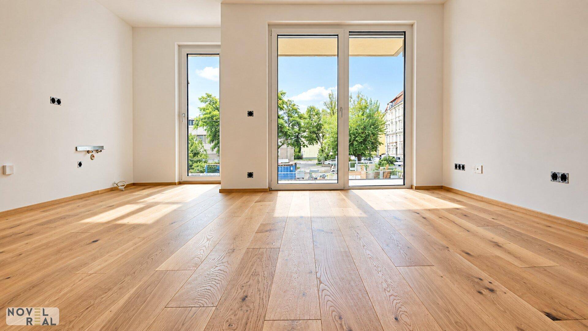 Lichtdurchfluteter Raum mit Holzdielenboden und Zugang zu einem Außenbereich.