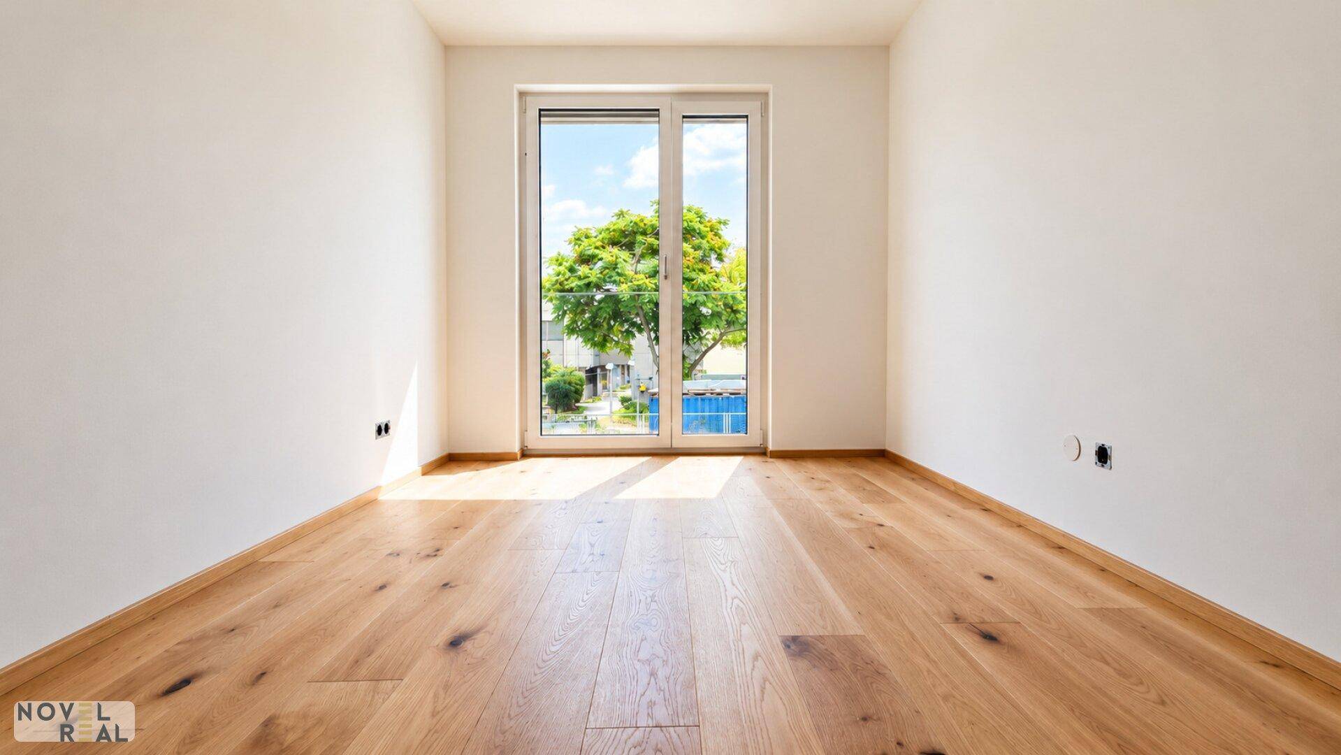 Helles Schlafzimmer mit Eichenparkett und großem Fenster mit Blick ins Grüne.