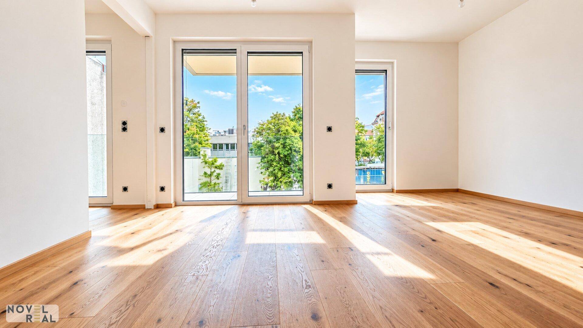 Heller Wohnraum mit Eichenparkett und breiter Schiebetür, die Zugang zu einem Balkon bietet.
