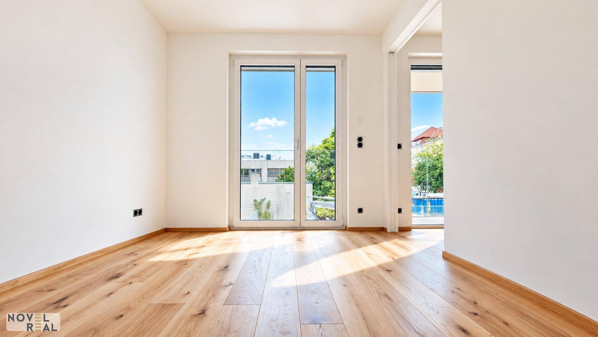Unmöblierter Raum mit hellem Parkettboden und großen Fenstern, die eine angenehme Atmosphäre schaffen.