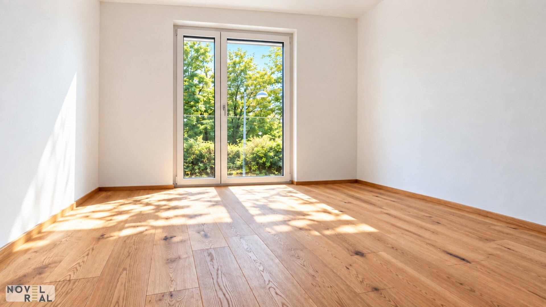 Sonniger, leerer Raum mit Holzboden und Zugang zu einem Balkon oder einer Terrasse mit Grünblick.
