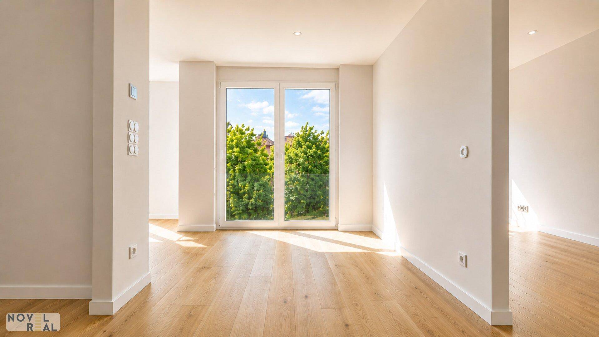 Gemütlicher Wohnbereich mit Holzboden und einem großen Fenster, das viel Licht spendet.