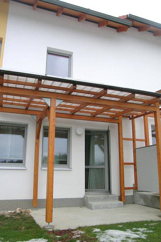 Überdachte Terrasse mit Holzpergola und Zugang zum Gartenbereich.
