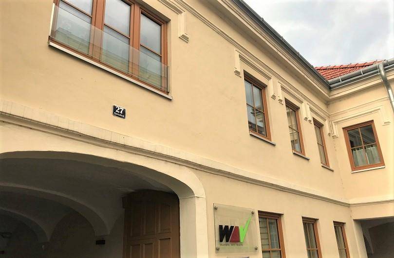 Traditionelle Fassade eines Altbaus in hellem Beige mit Holzelementen und einem Durchgang.