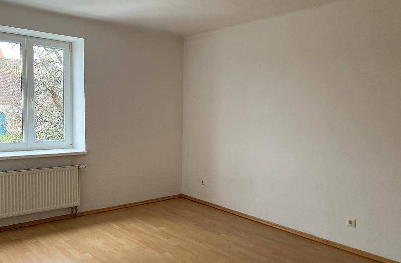 Unmöbliertes Zimmer mit hellem Laminatboden und weiß gestrichenen Wänden, ideal für neue Mieter.