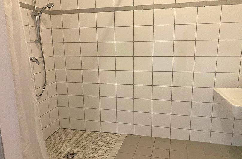 Duschbereich in einem Badezimmer mit weißen Fliesen und einer Duschvorrichtung.
