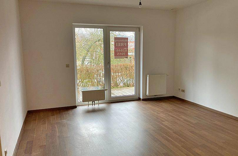 Heller Raum mit Laminatboden und Zugang zu einem Balkon oder einer Terrasse.
