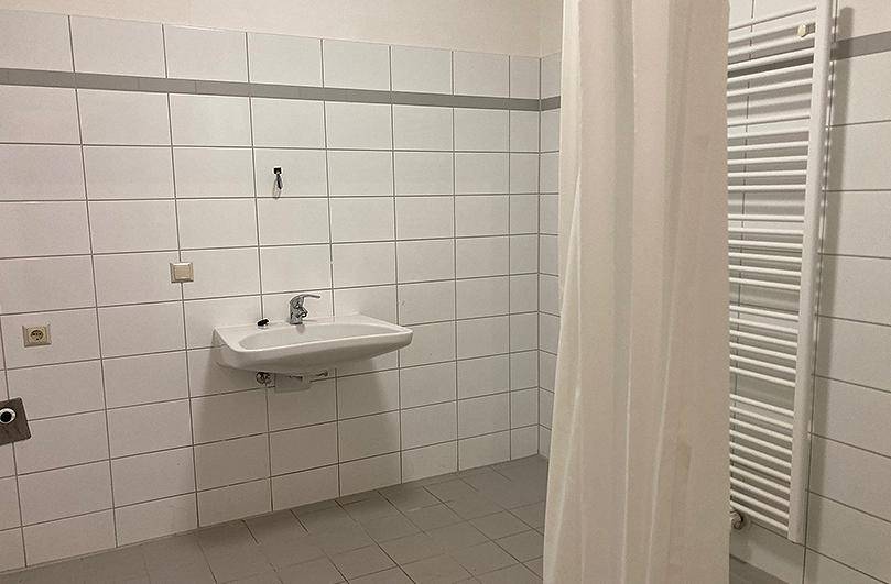 Gefliestes Badezimmer mit Waschbecken, Heizkörper und Duschvorhang.