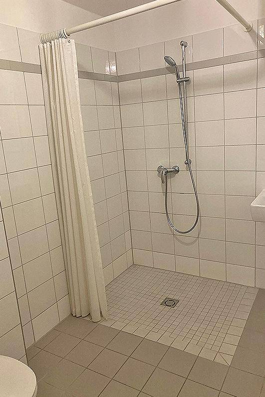 Funktionales Badezimmer mit gefliester Dusche und Duschvorhang, in hellen Farbtönen gehalten.