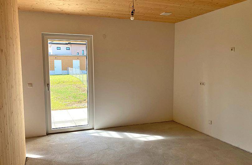 Leerer Raum mit großem Fenster und Zugang zum Garten, ideal für individuelle Gestaltung.